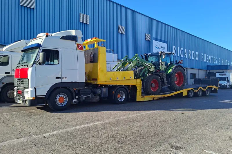 Tractora con góndola transportando tractores hasta un concesionario agrícola.