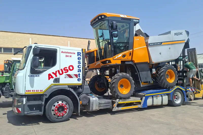Grúa de Ayuso con una máquina vendimiadora cargada sobre la góndola.